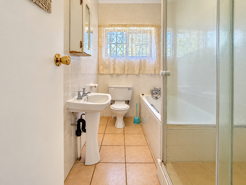 A functional bathroom featuring a pedestal sink, toilet, bathtub, and separate shower enclosure with tiled finishes throughout.