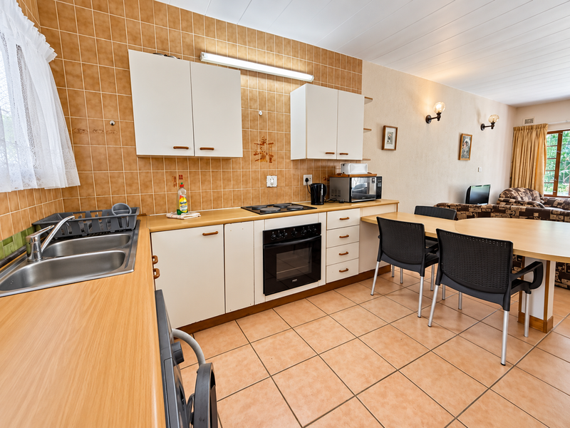 Open-plan kitchen and dining area featuring tiled flooring, built-in cabinetry, laminate countertops, and integrated cooking appliances.