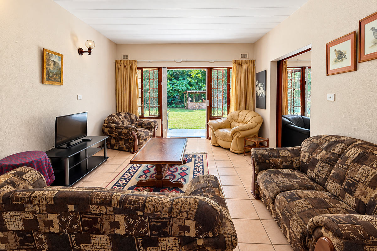 Spacious living room featuring tiled flooring and double glass doors that open directly onto a private garden area.
