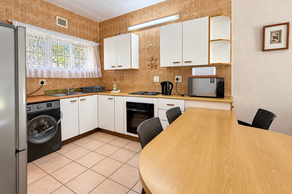 A functional kitchen featuring built-in cabinetry, a laminate countertop, integrated oven and hob, and tiled finishes throughout.