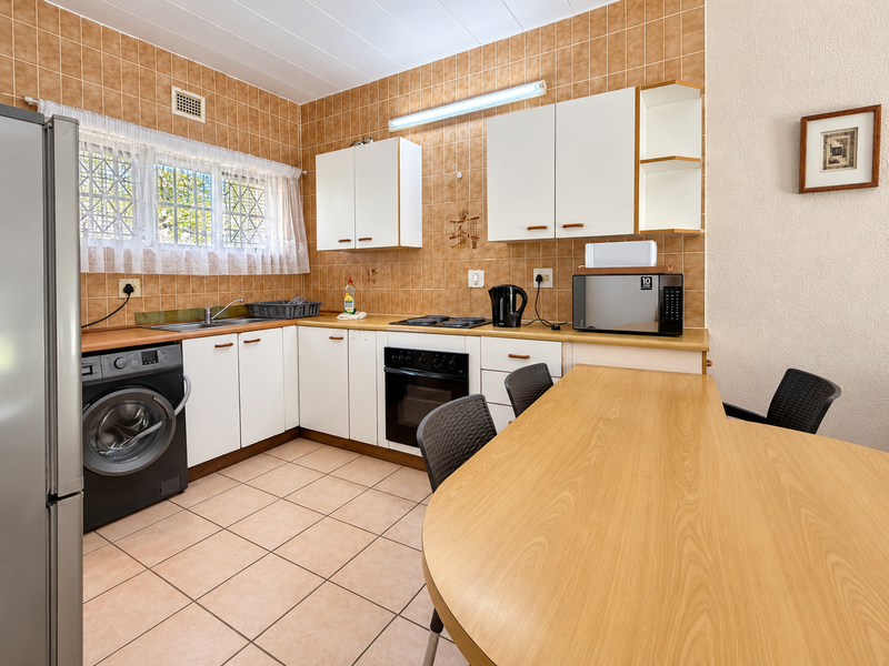 A functional kitchen featuring built-in cabinetry, a laminate countertop, integrated oven and hob, and tiled finishes throughout.