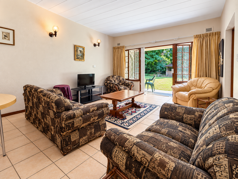 A spacious living room featuring tiled flooring and large sliding glass doors that provide direct access to the garden area.