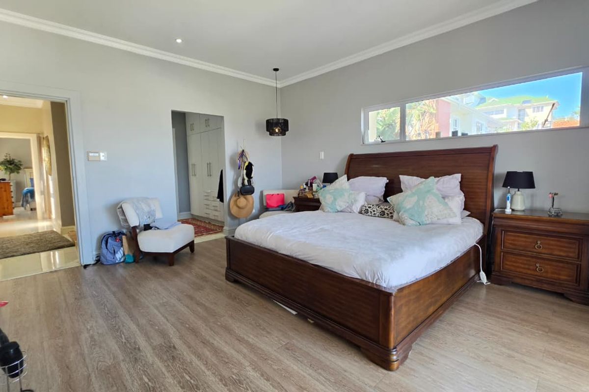 Spacious bedroom featuring light-toned laminate flooring, neutral walls, recessed downlighting, and a walk-in closet area with built-in cabinetry.