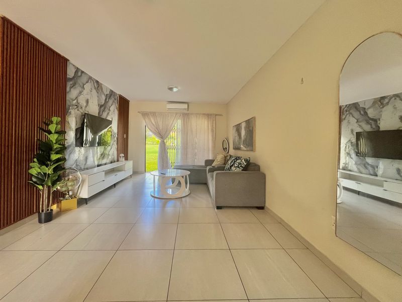A bright living room featuring a modern marble-effect feature wall with vertical timber accents, tiled flooring, and direct access to an outdoor area.
