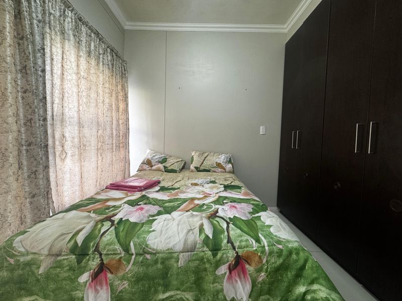 A bedroom featuring dark wood built-in cupboards, tiled flooring, and decorative cornice detailing.