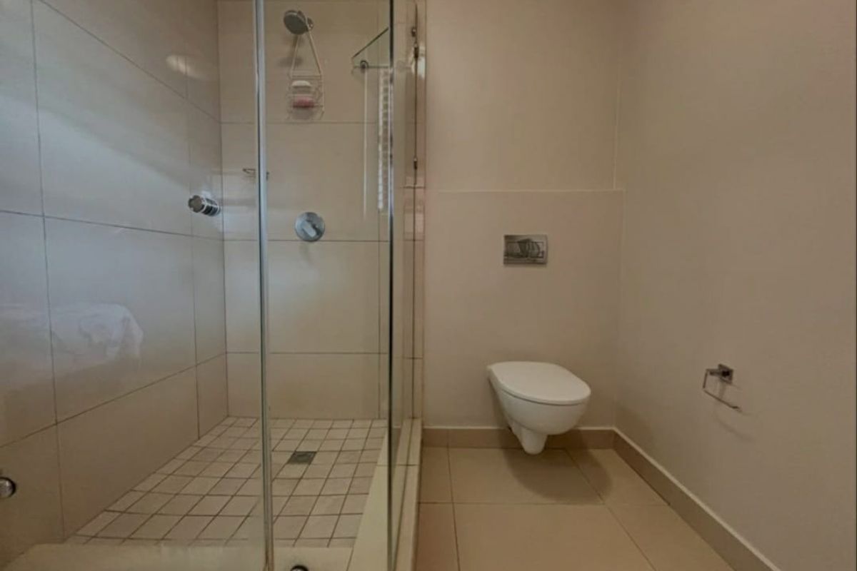 A clean, modern bathroom featuring a glass-enclosed shower and a wall-mounted toilet with a concealed cistern.