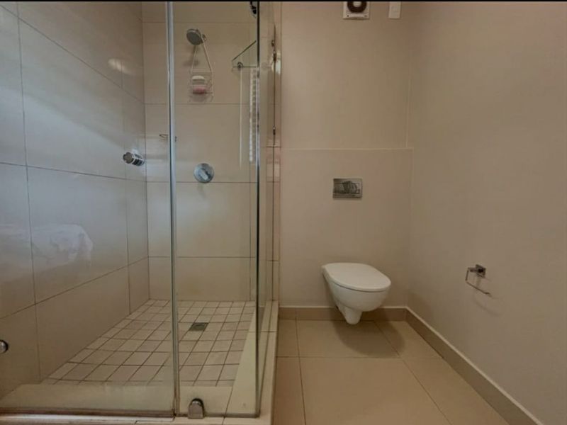 A clean, modern bathroom featuring a glass-enclosed shower and a wall-mounted toilet with a concealed cistern.
