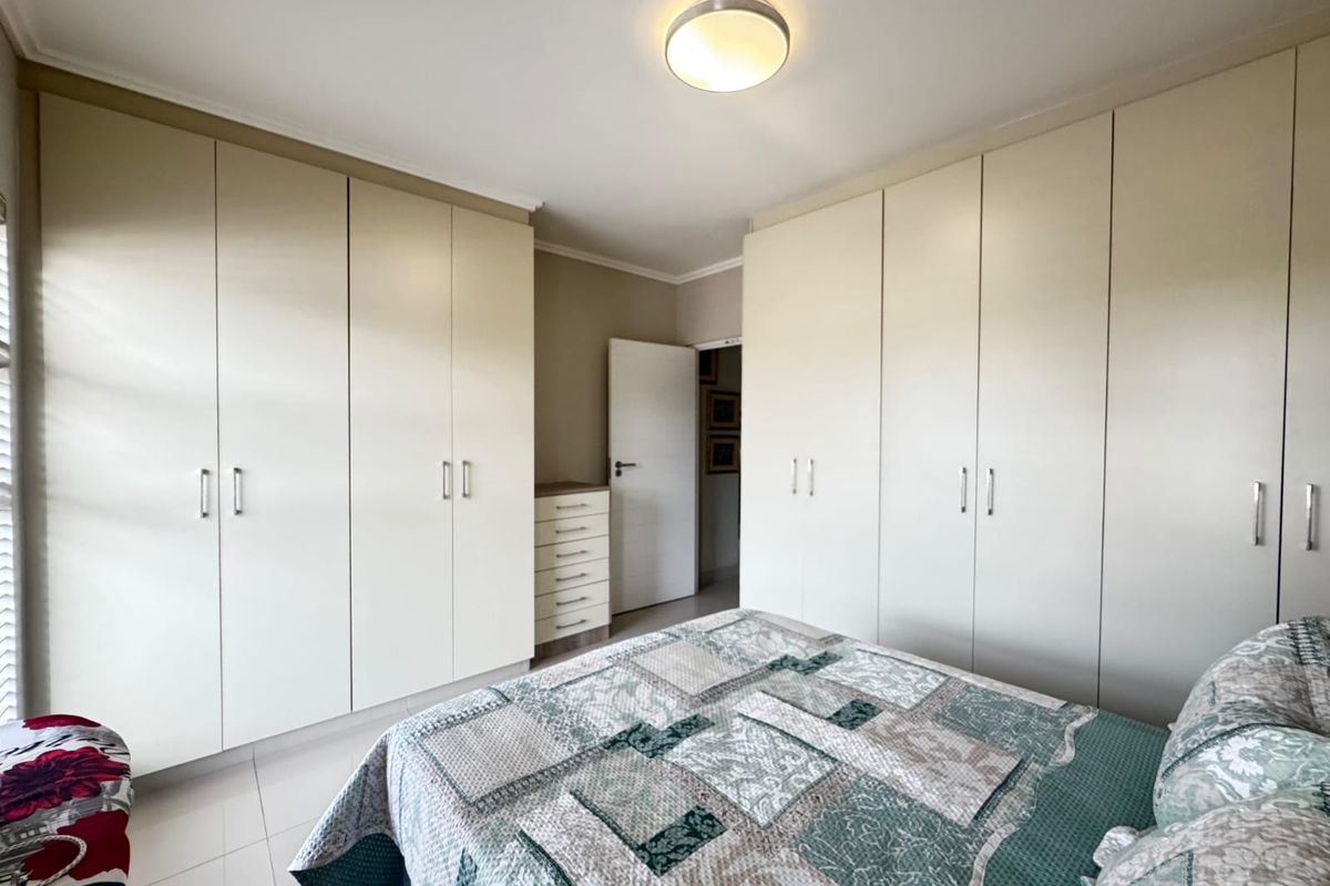 A well-maintained bedroom featuring extensive built-in cupboards providing ample storage space and neutral tiled flooring.