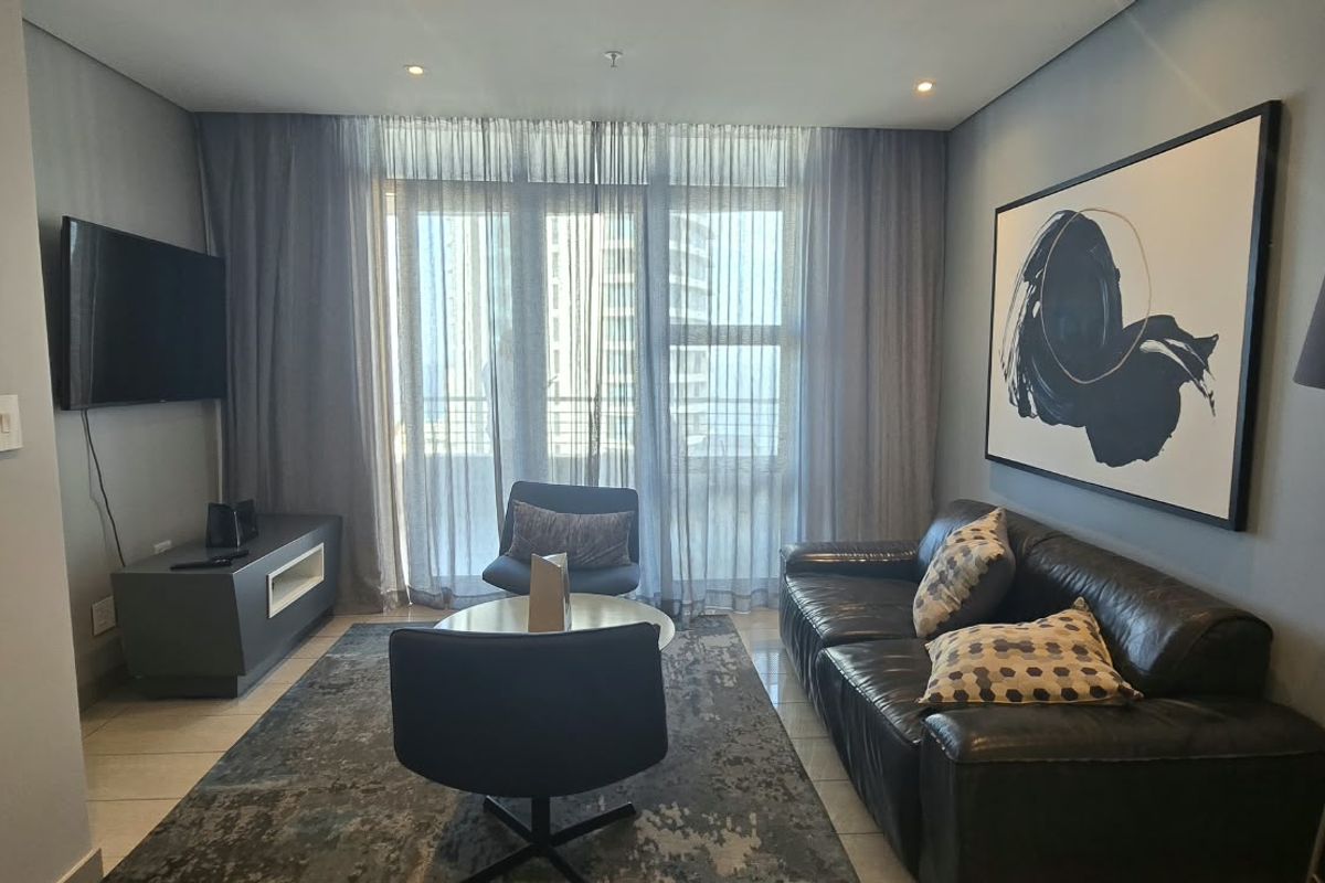 A modern living room featuring tiled flooring, recessed downlighting, and a large sliding glass door providing access to the balcony.