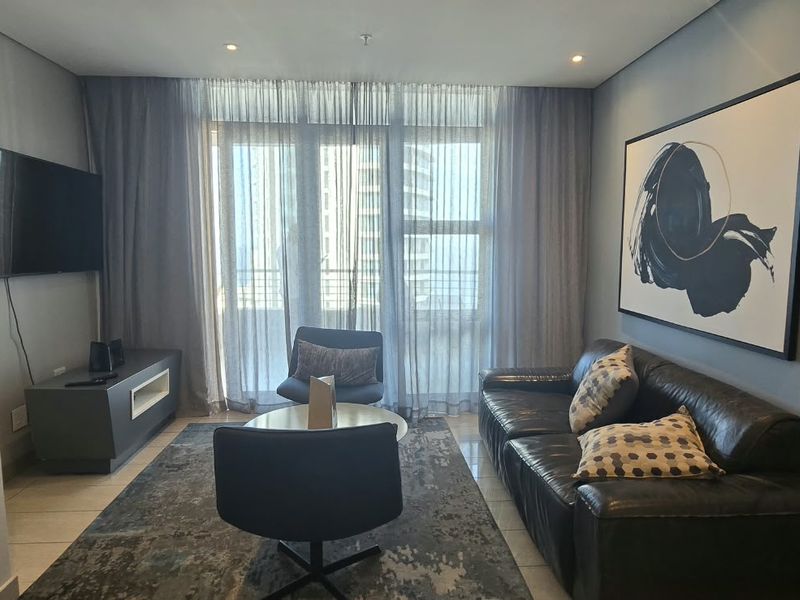 A modern living room featuring tiled flooring, recessed downlighting, and a large sliding glass door providing access to the balcony.