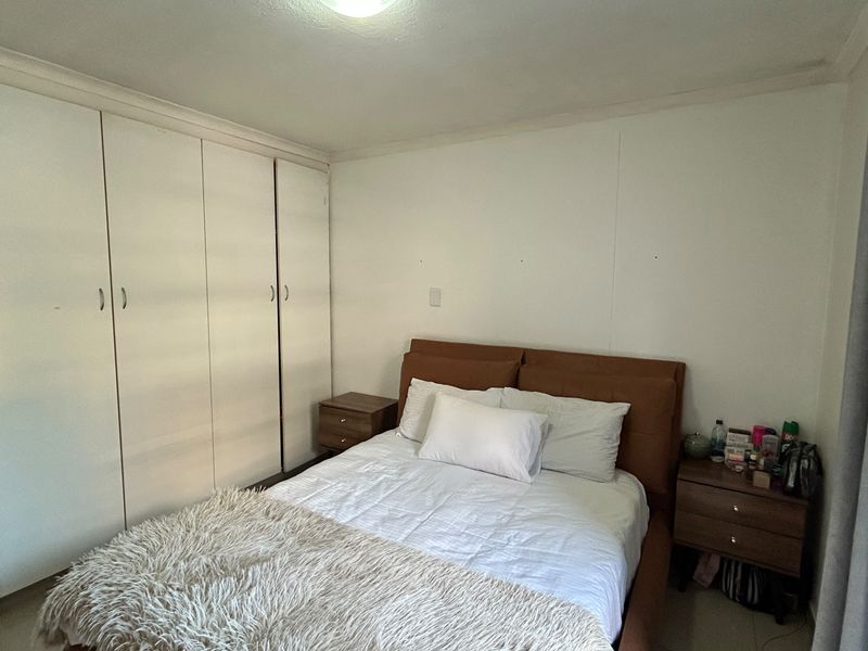A functional bedroom featuring floor-to-ceiling built-in cupboards and neutral wall finishes, providing a clean and practical space.