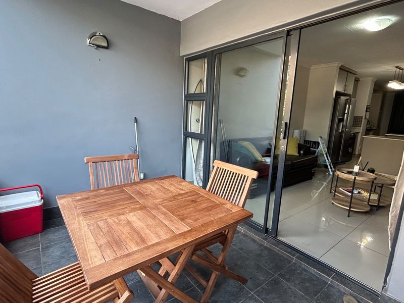 A covered balcony featuring tiled flooring, a metal railing, and a large sliding glass door providing access to the interior living area.