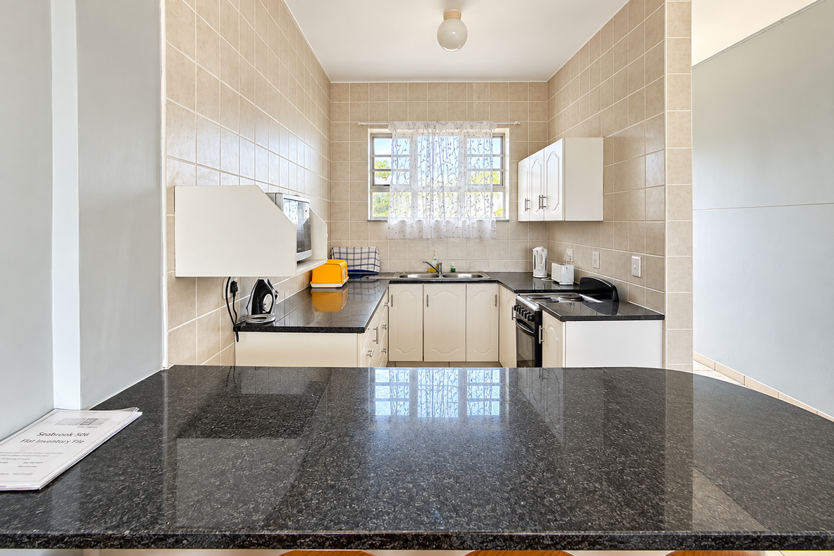 A functional kitchen featuring granite countertops, a breakfast bar, tiled walls, and built-in cabinetry with a freestanding stove.