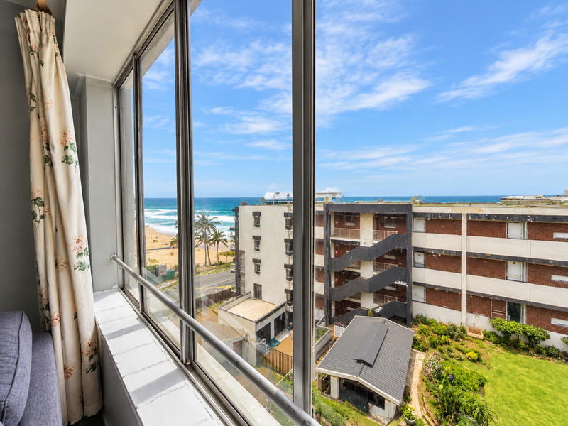 A clear view of the ocean and surrounding coastal apartment complex from an elevated interior vantage point.