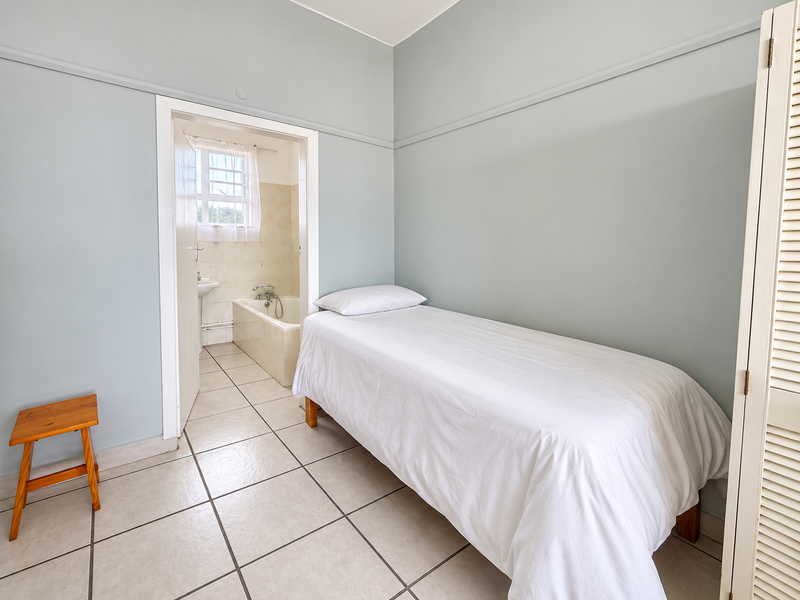 A bedroom featuring tiled flooring, picture rails, and louvered closet doors, with an adjoining bathroom visible through the doorway.