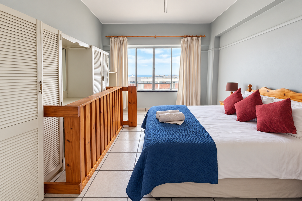A bedroom featuring tiled flooring, a built-in wardrobe with louvered doors, a ceiling fan, and a window with views.
