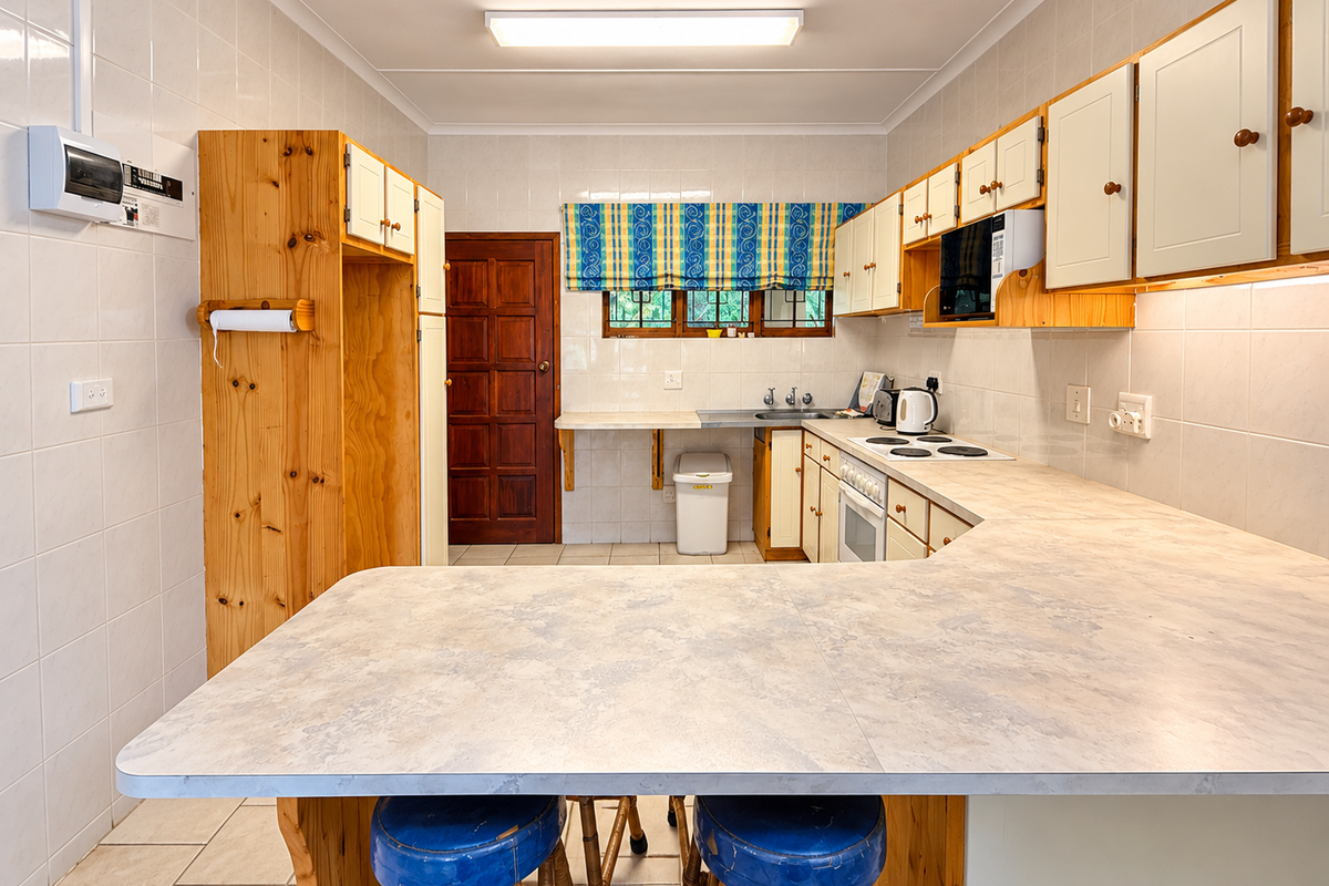 A functional kitchen featuring tiled walls and flooring, ample built-in cabinetry, a breakfast counter, and integrated cooking appliances.
