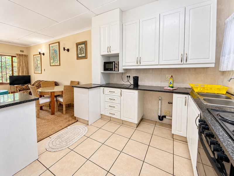 Open plan kitchen and dining area featuring white cabinetry, granite countertops, tiled flooring, and integrated cooking appliances.