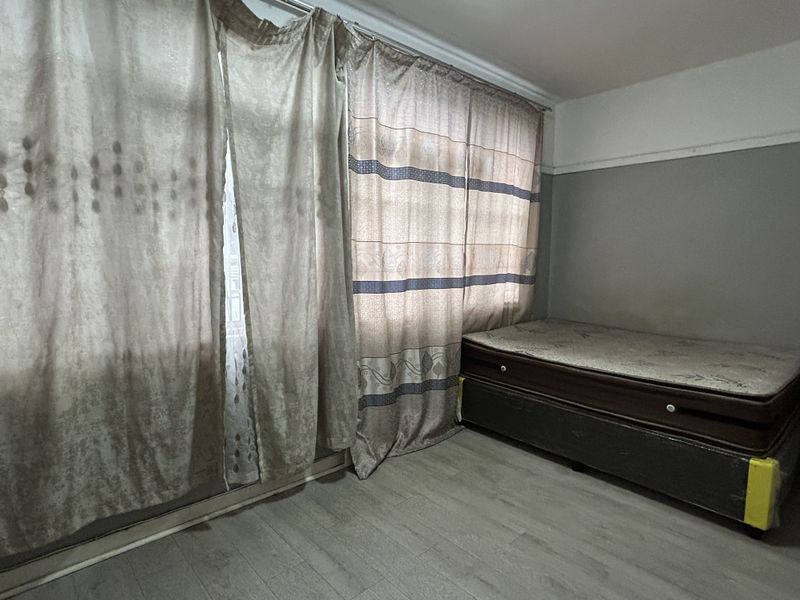 A bedroom featuring laminate flooring and large window curtains, providing a neutral base for personalization.
