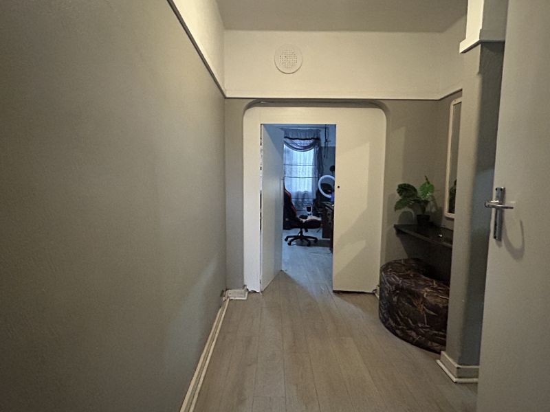 A neutral-toned hallway featuring laminate flooring and a classic picture rail, providing a clean transition between living spaces.
