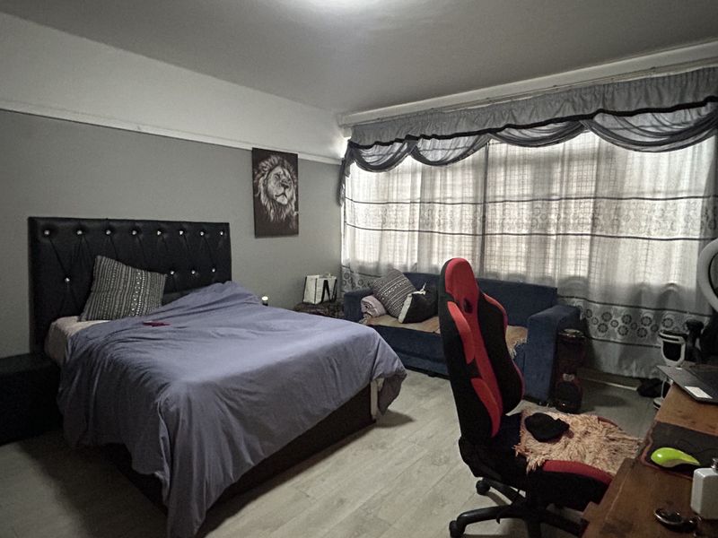 A spacious bedroom featuring laminate flooring and a classic picture rail, offering a comfortable layout with ample natural light through the window.