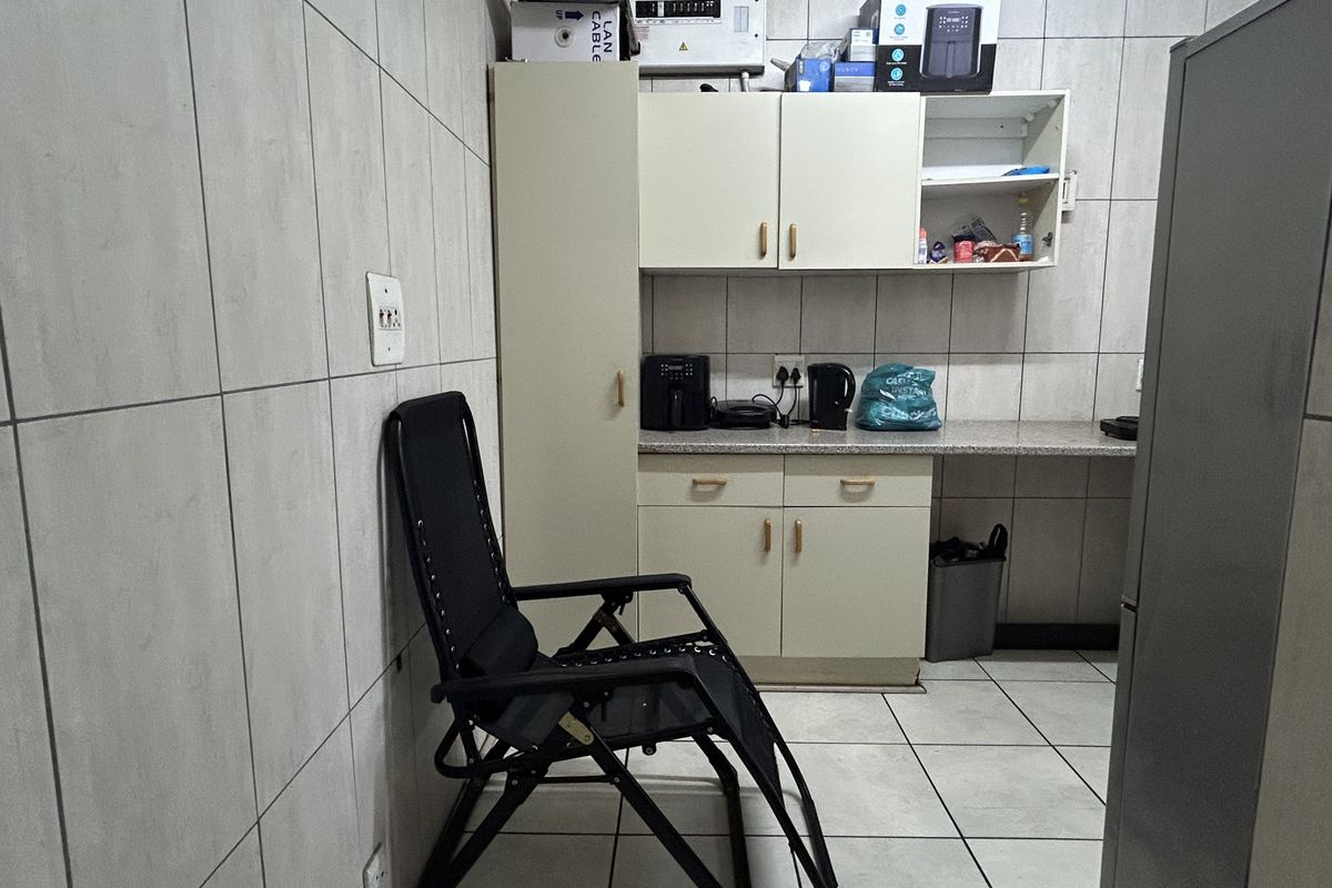 A functional kitchen area featuring tiled walls and flooring, built-in cabinetry, and a stone countertop, providing a practical workspace for daily use.