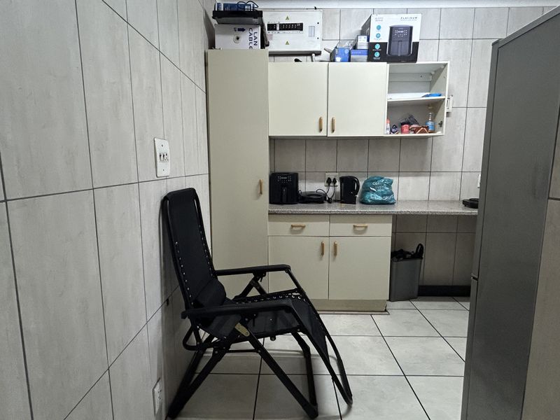 A functional kitchen area featuring tiled walls and flooring, built-in cabinetry, and a stone countertop, providing a practical workspace for daily use.