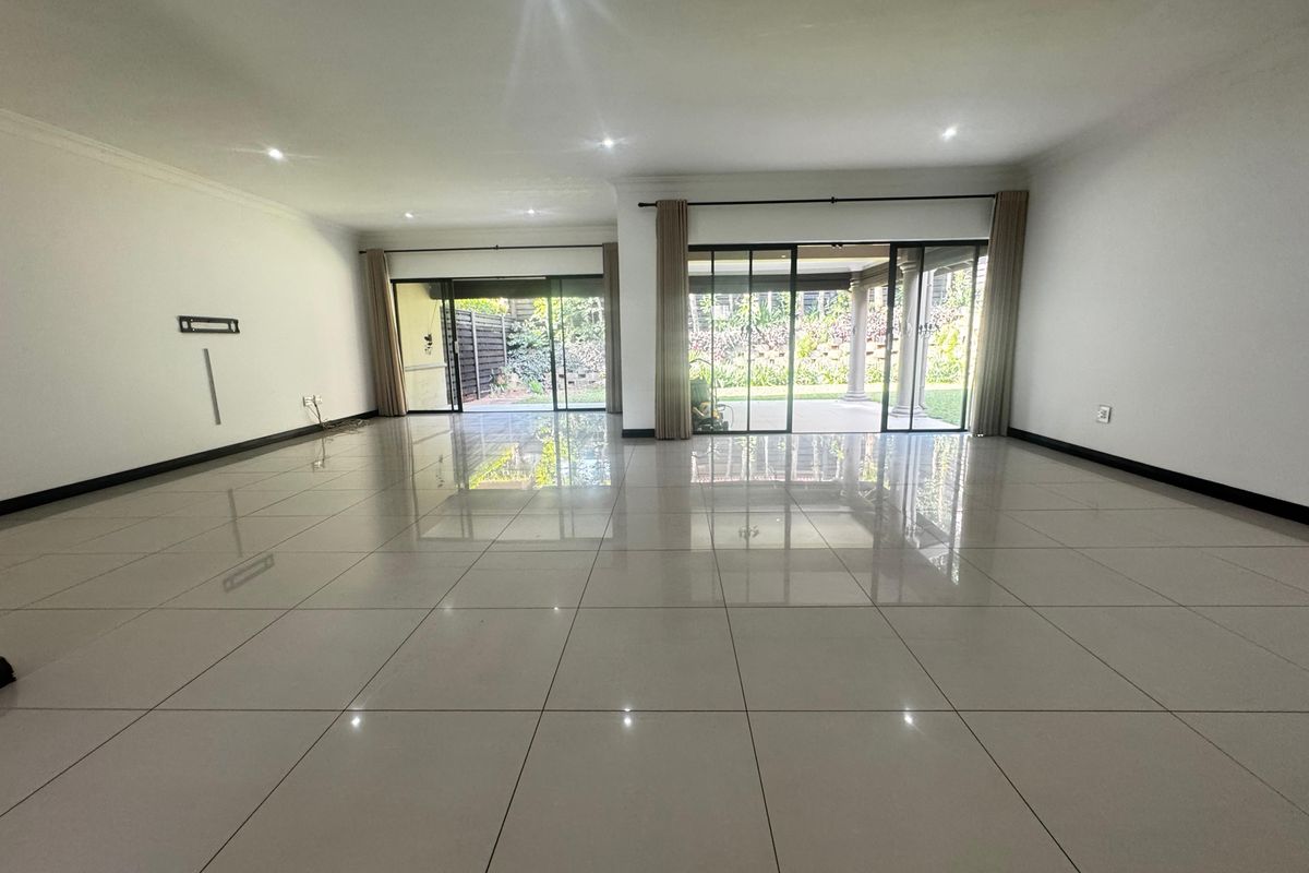 Spacious, light-filled living area featuring large format porcelain tiles, recessed lighting, and expansive sliding glass doors opening to the rear patio and garden.
