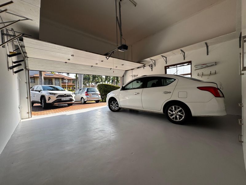 Spacious double garage featuring a clean painted concrete floor, automated sectional door, and wall-mounted storage brackets for organized parking and utility use.