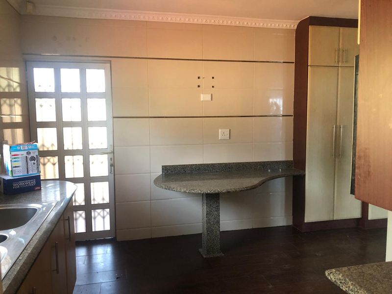 Kitchen area featuring granite countertops, built-in cabinetry, and tiled splashbacks, providing a functional space ready for updates.