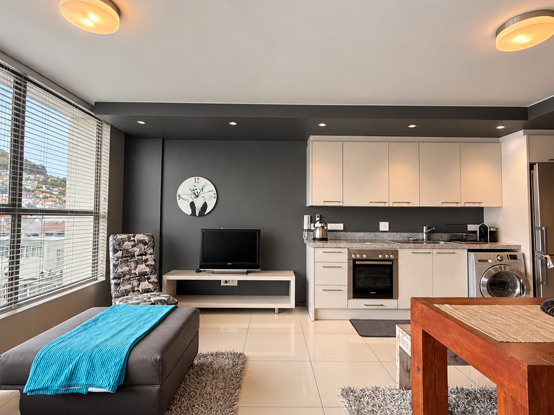 Modern open-plan living area featuring a sleek kitchen with built-in appliances, granite countertops, and expansive windows offering natural light and urban views.