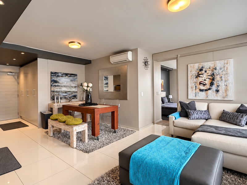 Modern open-plan living and dining area featuring tiled floors, recessed lighting, built-in cabinetry, and an integrated air conditioning unit.