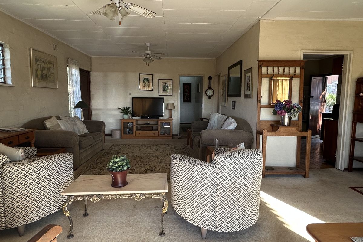 Spacious living room featuring carpeted flooring and dual ceiling fans, offering a comfortable layout with access to adjacent rooms.