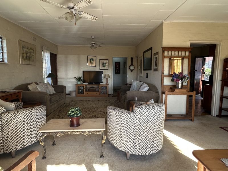 Spacious living room featuring carpeted flooring and dual ceiling fans, offering a comfortable layout with access to adjacent rooms.