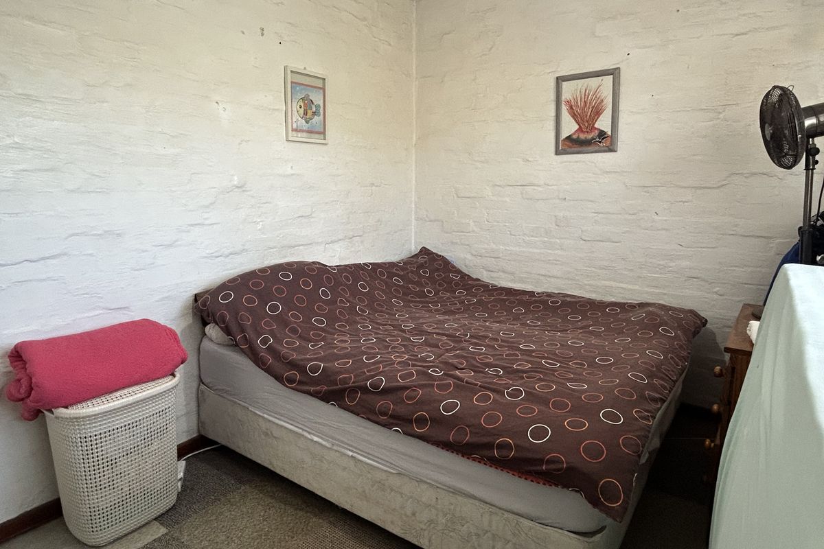A bedroom featuring painted brick walls and carpeted flooring, offering a blank canvas for potential cosmetic updates and interior design improvements.