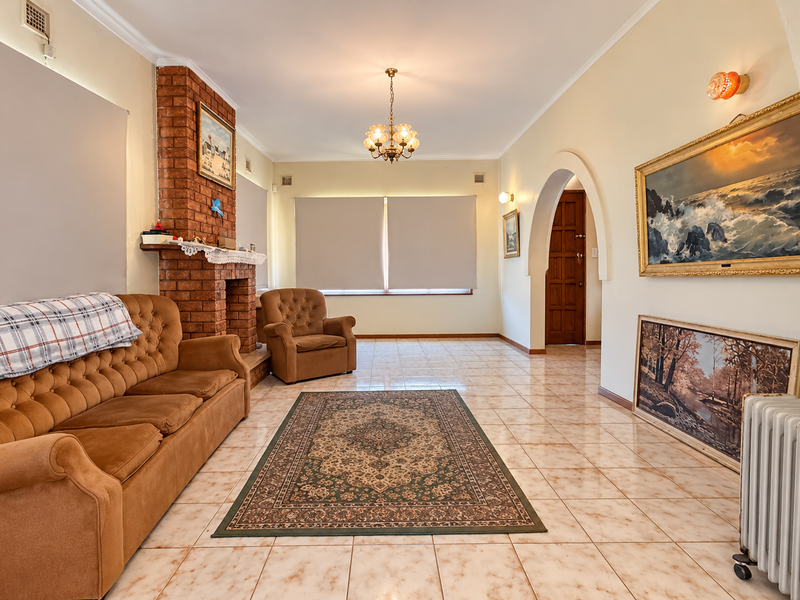 Spacious living room featuring a classic brick fireplace, ceramic tile flooring, and an elegant arched doorway leading to the rest of the home.