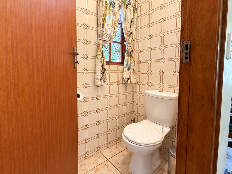 A compact guest bathroom featuring classic patterned wall tiles, tiled flooring, and a leaded glass window.