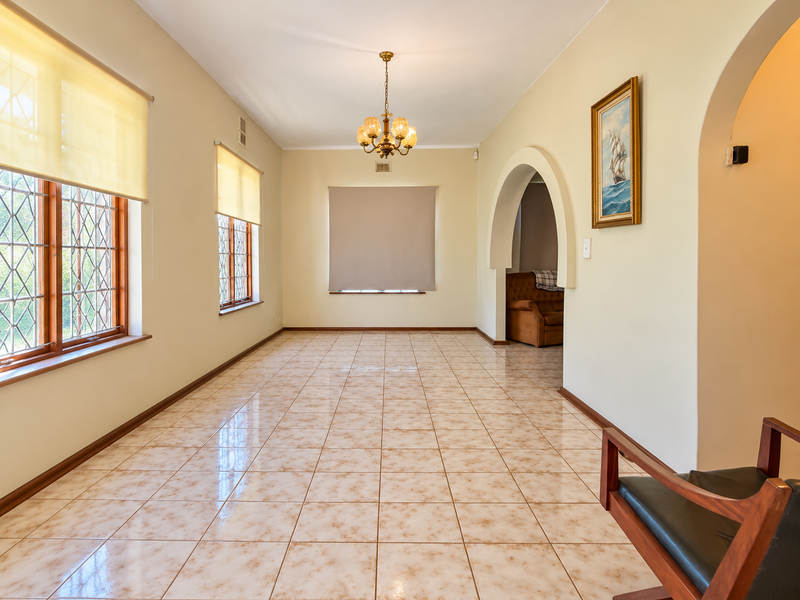 Spacious living area featuring ceramic tile flooring, arched architectural detailing, and classic leaded glass windows, offering a bright and versatile living space.