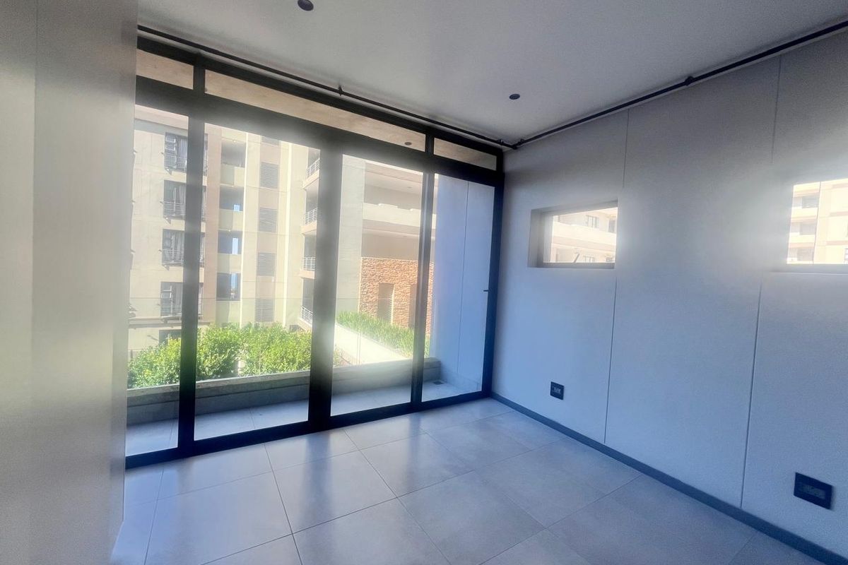 A bright, modern, and empty bedroom featuring large sliding glass doors that open to a balcony, tiled floors, and recessed lighting.