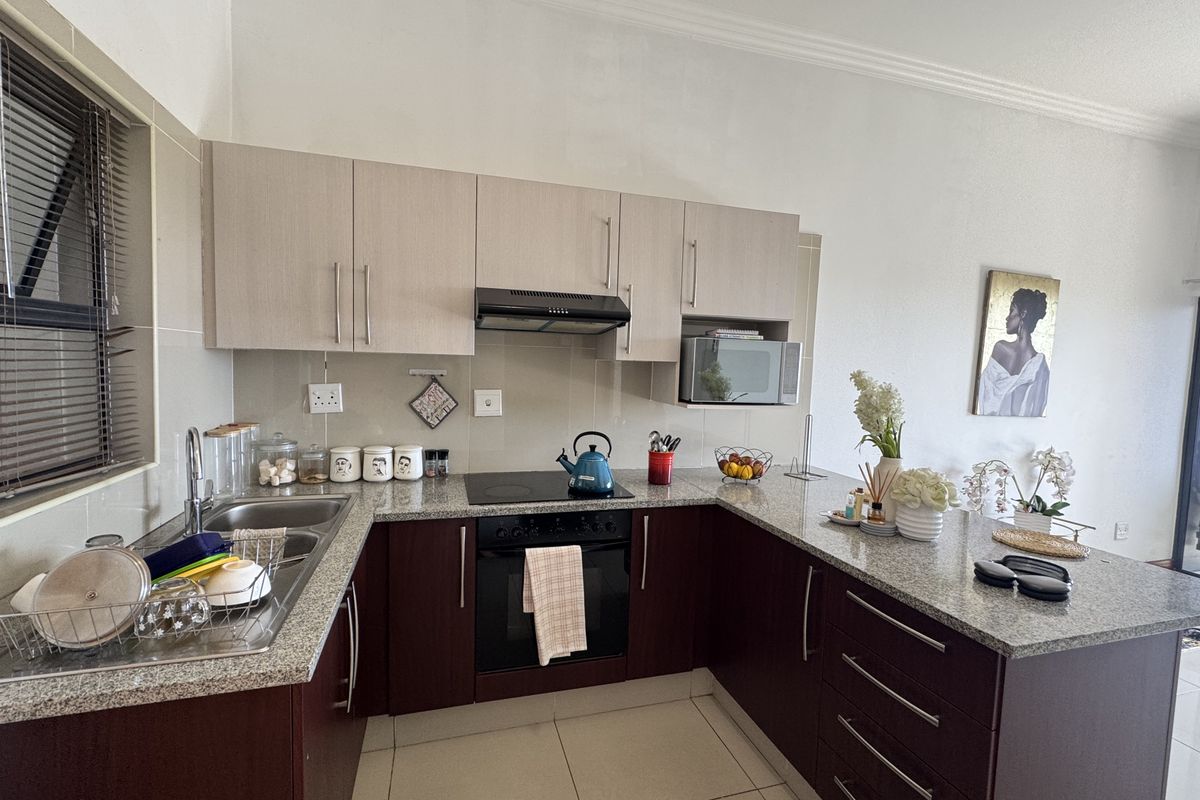Modern U-shaped kitchen featuring granite countertops, built-in oven, electric hob, extractor fan, and ample upper and lower cabinetry storage.