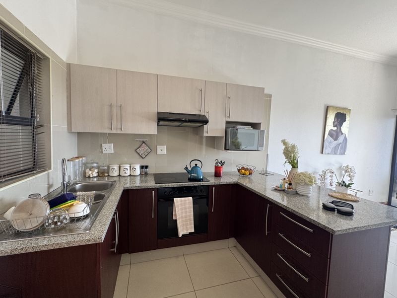 Modern U-shaped kitchen featuring granite countertops, built-in oven, electric hob, extractor fan, and ample upper and lower cabinetry storage.