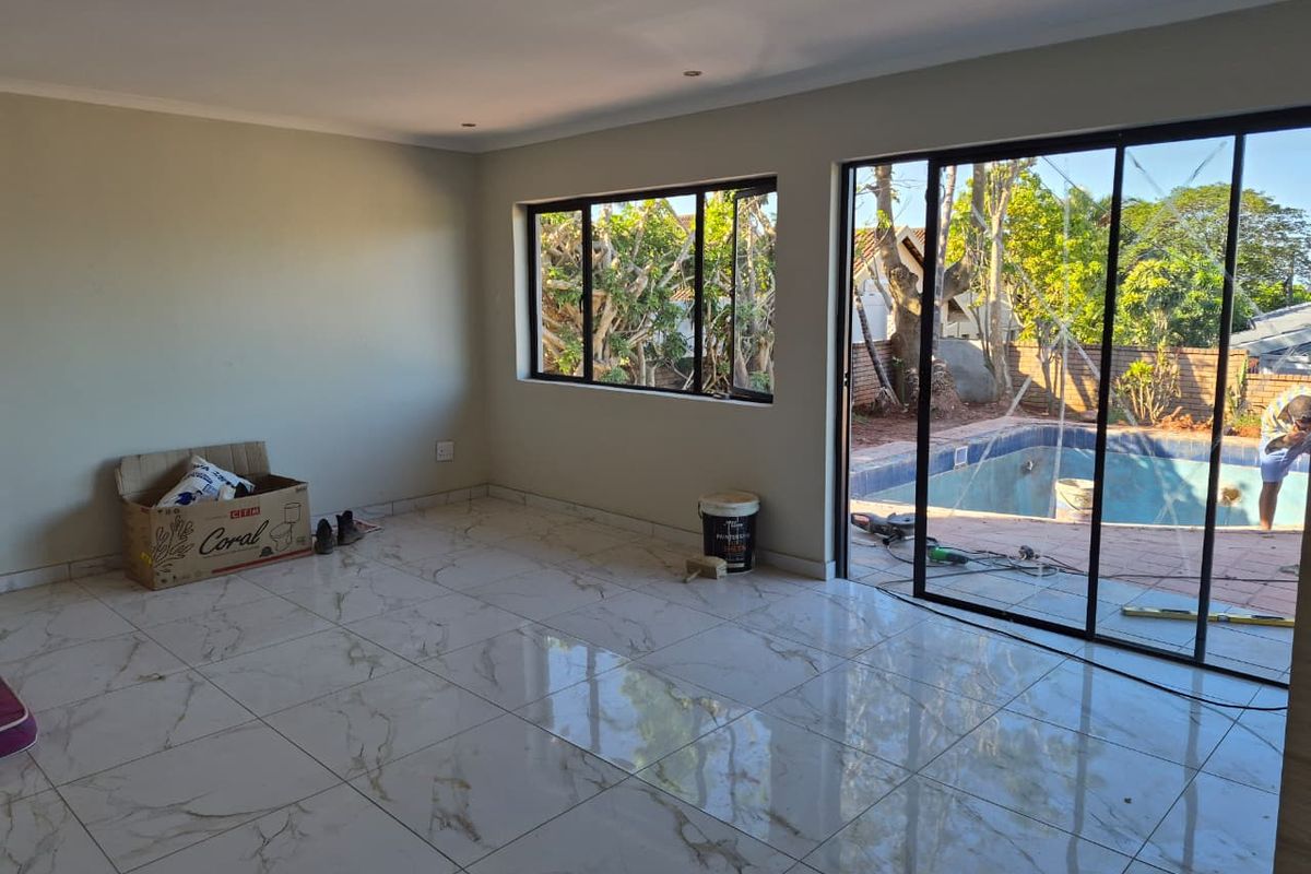 Spacious living area featuring polished marble-look floor tiles, recessed lighting, and large sliding doors opening to a pool area.