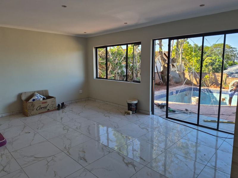 Spacious living area featuring polished marble-look floor tiles, recessed lighting, and large sliding doors opening to a pool area.