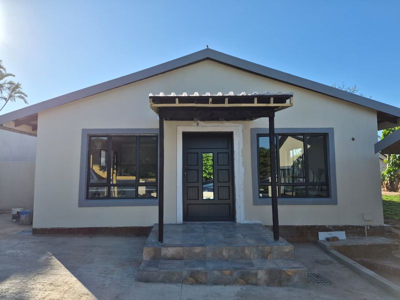 Front elevation of a house featuring a tiled entrance, covered porch area, and modern aluminium window frames, currently undergoing minor exterior finishing works.