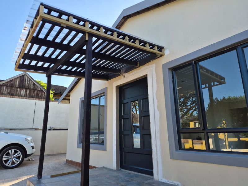 Front entrance featuring a timber pergola, tiled porch, and modern aluminium framed windows with dark grey trim.