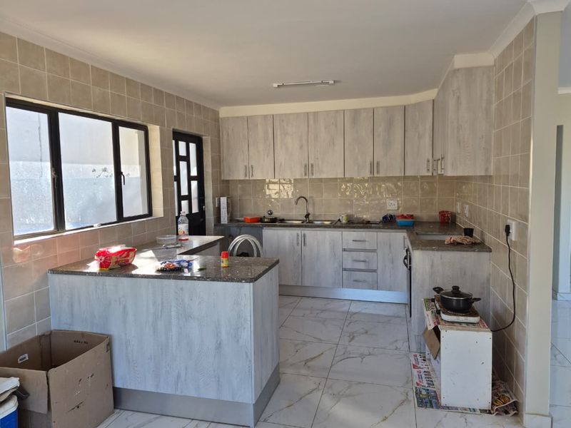 A functional kitchen featuring light wood-grain cabinetry, granite countertops, tiled backsplash, and tiled flooring with an integrated breakfast nook area.