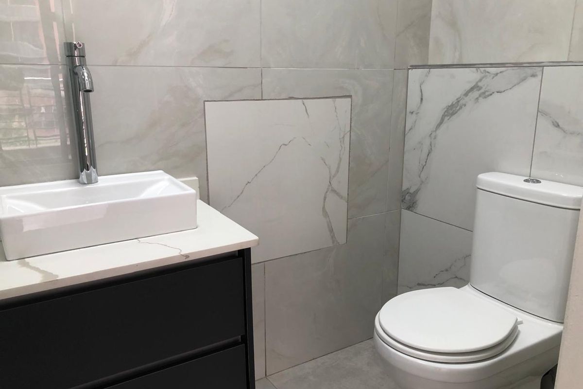 Modern bathroom featuring marble-effect wall tiles, a sleek vanity cabinet with a basin, and a standard toilet.