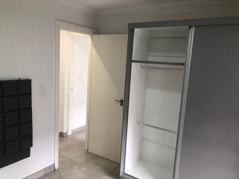 A bedroom featuring tiled flooring, coving, and a built-in wardrobe, with an open doorway leading to an adjacent hallway.