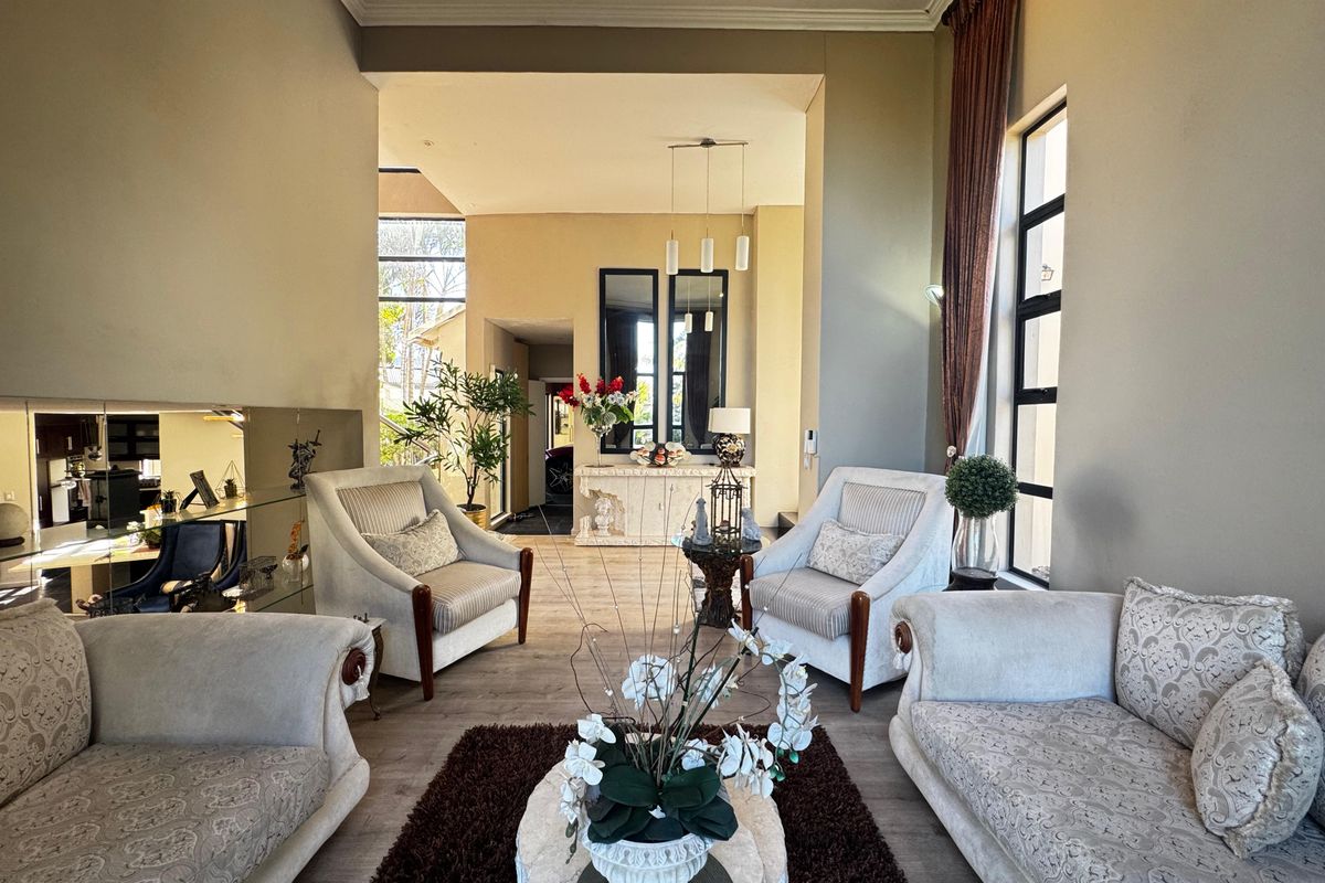 Spacious living room featuring high ceilings, large windows for natural light, laminate flooring, and elegant mirrored wall accents.