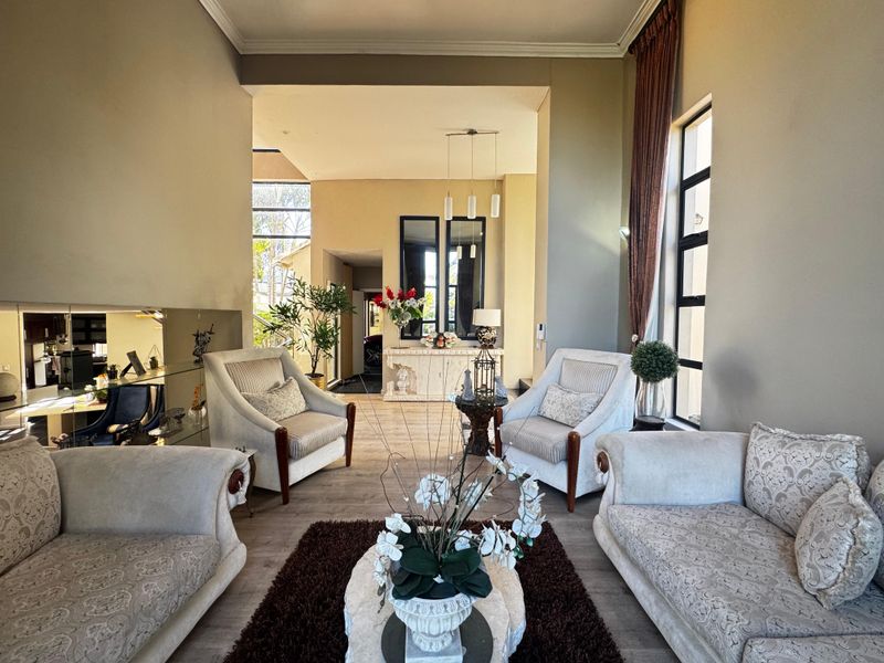 Spacious living room featuring high ceilings, large windows for natural light, laminate flooring, and elegant mirrored wall accents.